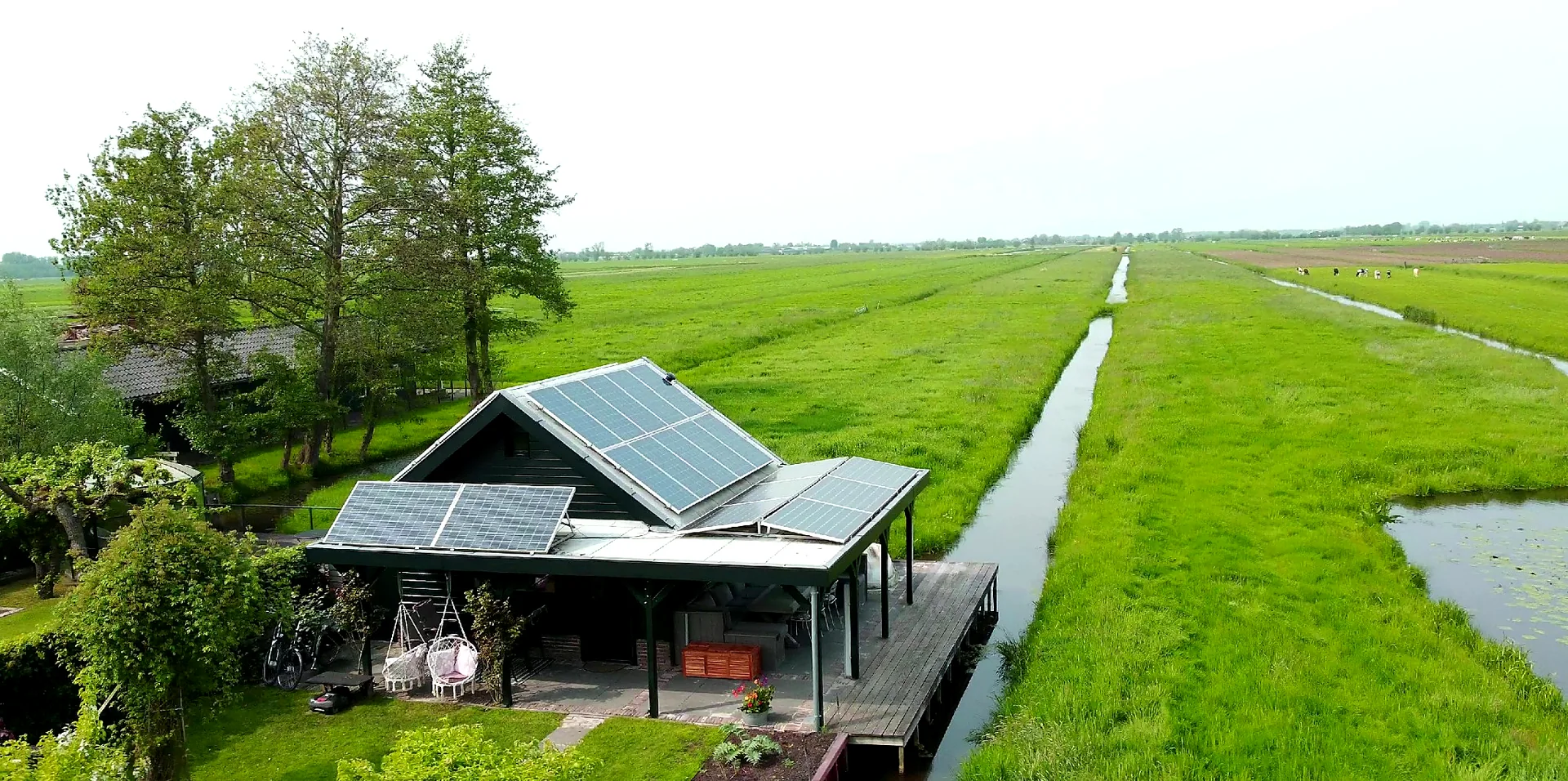 Aerial view of the holiday cottage Slapen in de Polder surrounded by water and green polder landscape in Bergambacht